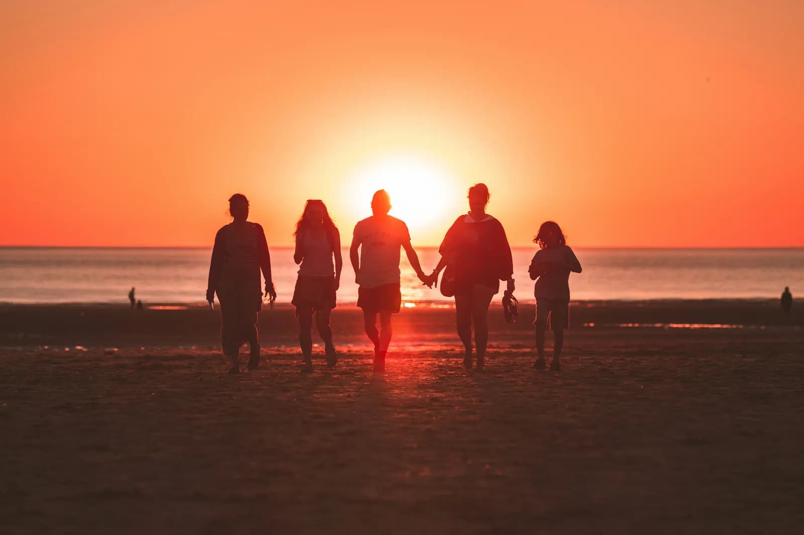 A family walks along the beach at sunset